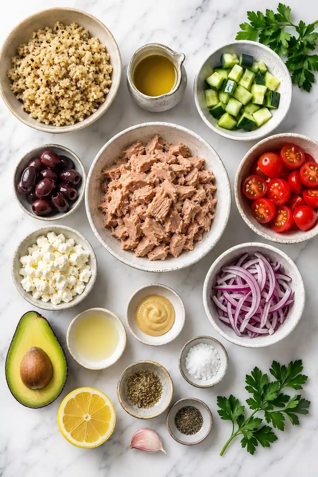 Flat lay of Mediterranean tuna bowl ingredients including tuna quinoa vegetables feta cheese olives and lemon dressing ingredients