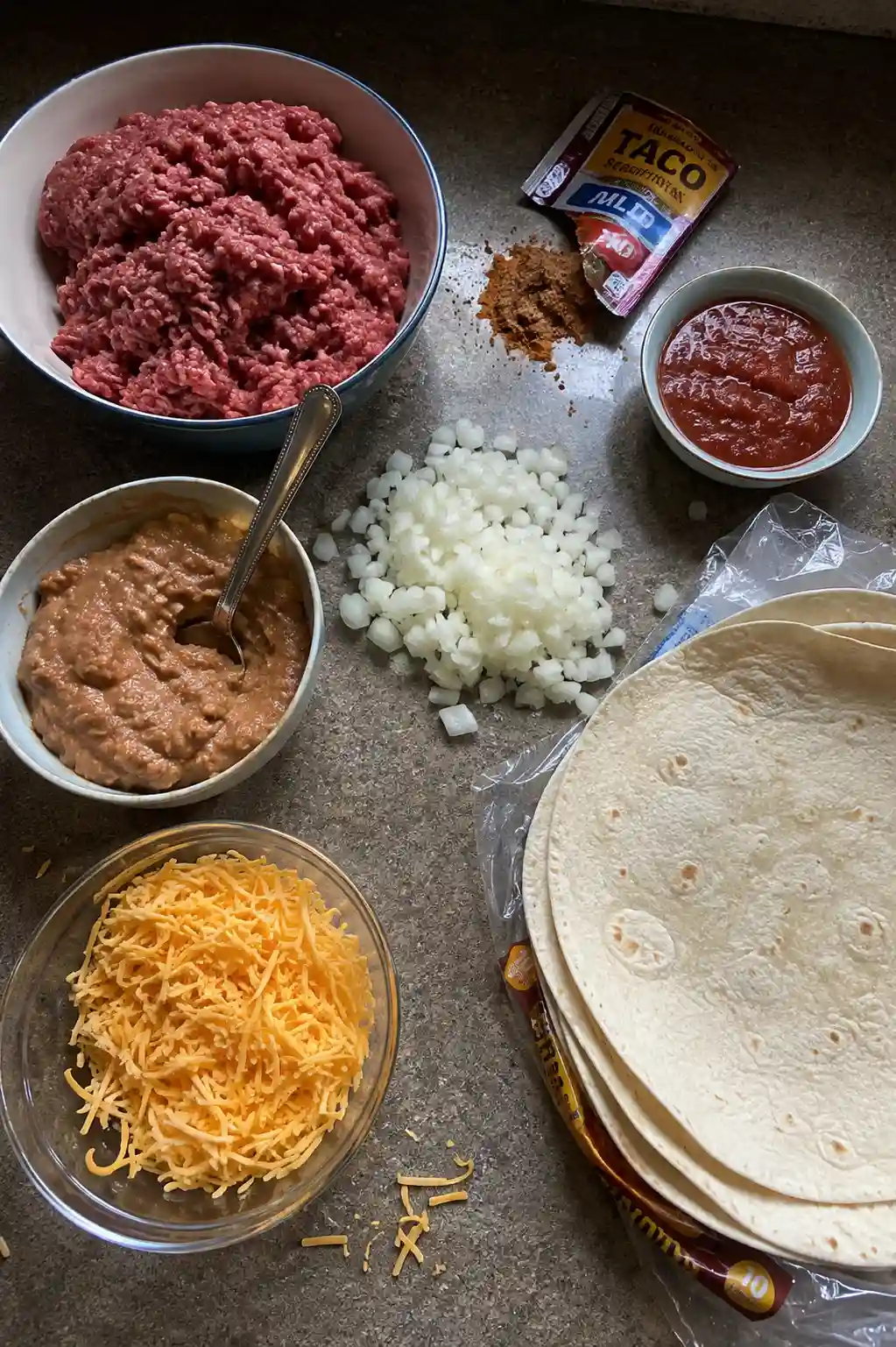 Ingredients for beef and cheese chimichangas including ground beef, tortillas, and cheese