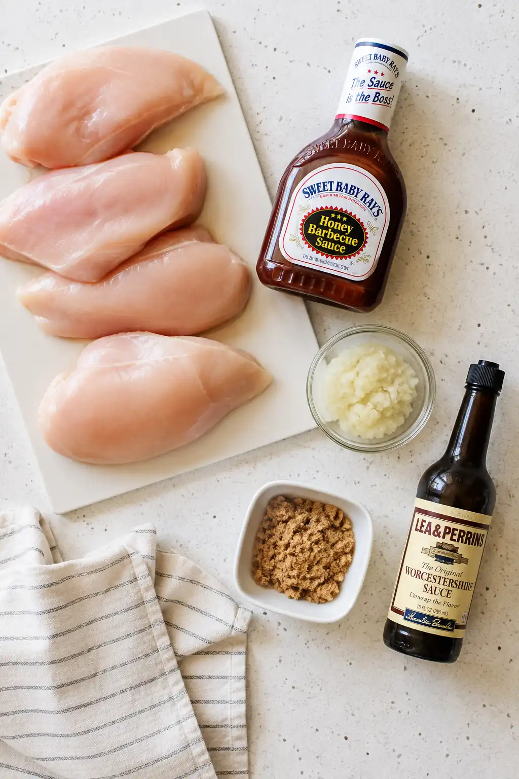 Ingredients for slow cooker BBQ chicken including chicken breasts, barbecue sauce, and onion