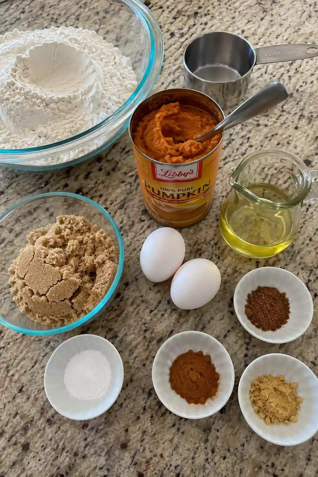Ingredients for pumpkin loaf including pumpkin puree, flour, eggs, and warm spices