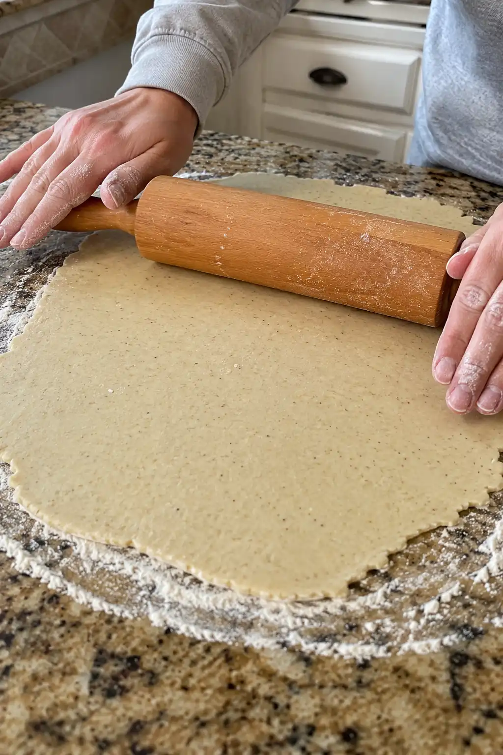 Rolling pin flattening sourdough cracker dough into a thin even layer