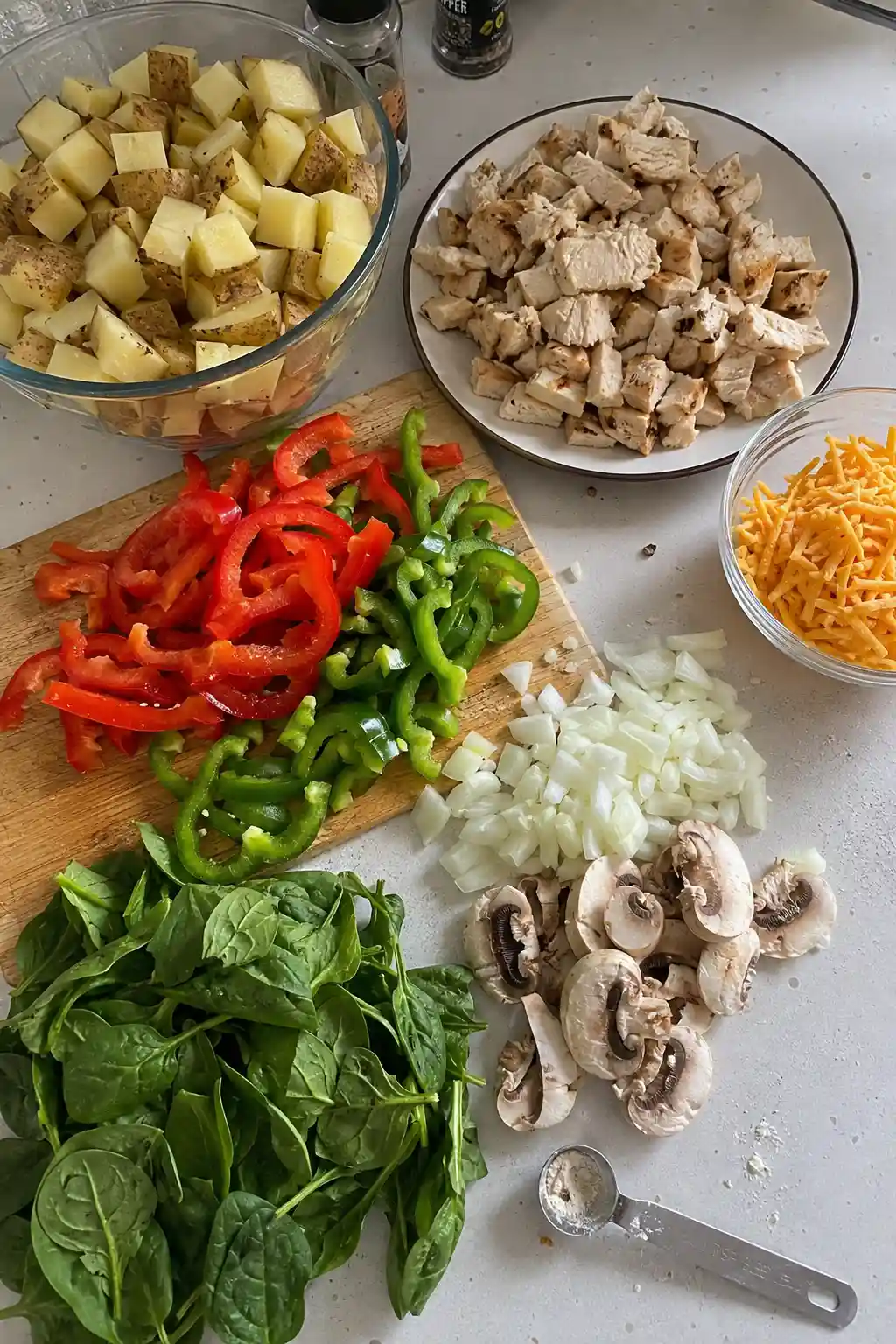 Ingredients for chicken hash including potatoes, chicken, bell peppers, and cheese