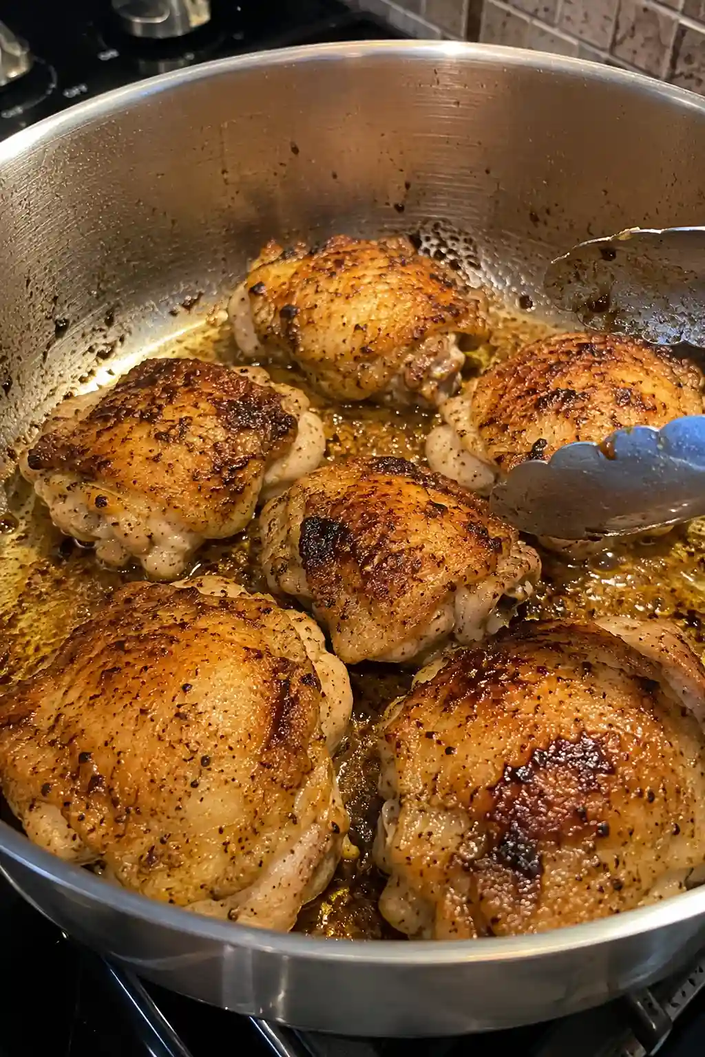 Seasoned chicken thighs searing golden brown in a large pot