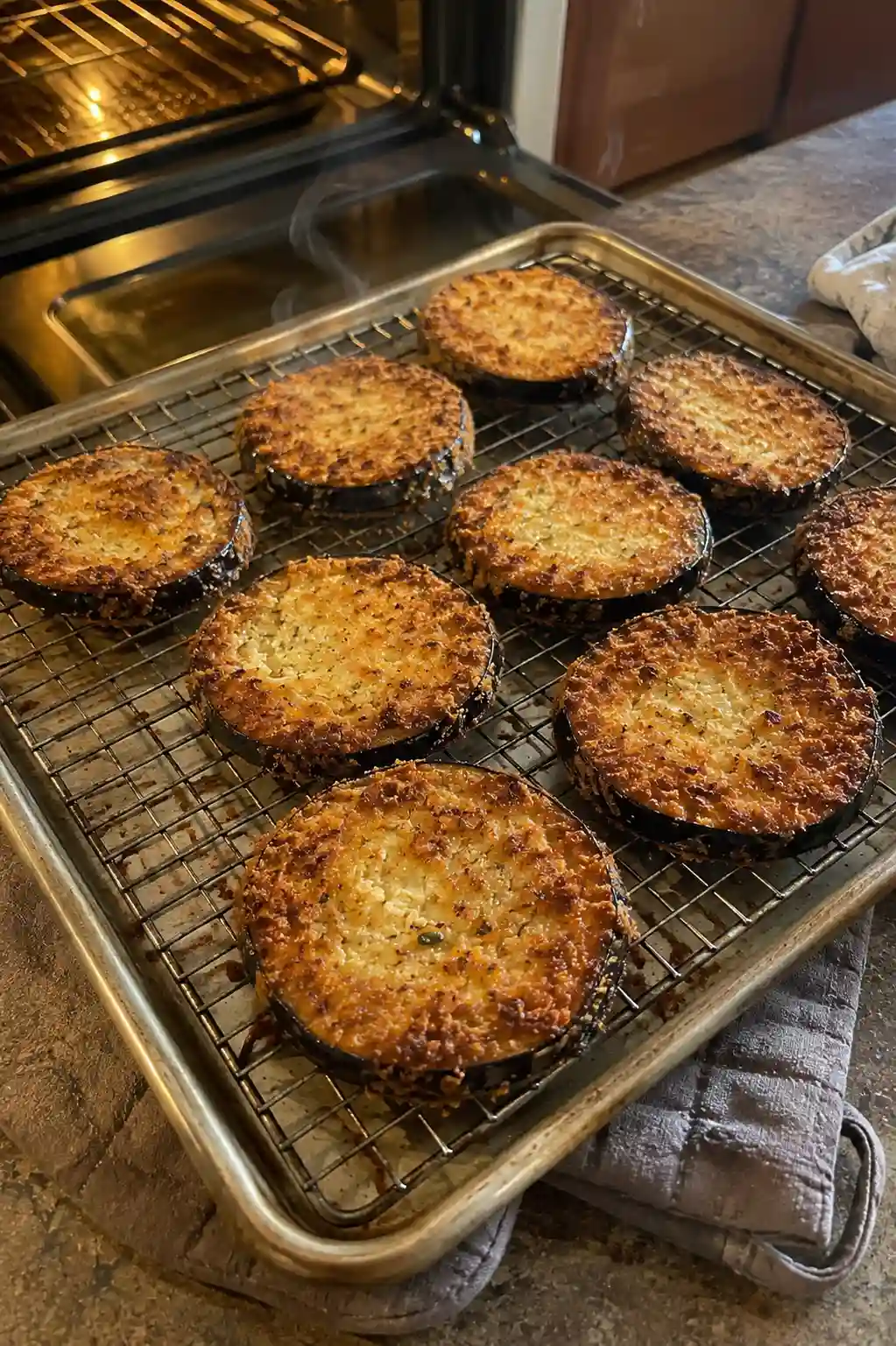 Golden breaded eggplant slices on a wire rack fresh out of the oven