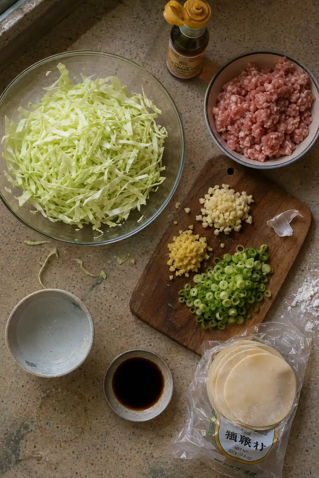 Ingredients for cabbage dumplings including shredded cabbage, pork, and dumpling wrappers