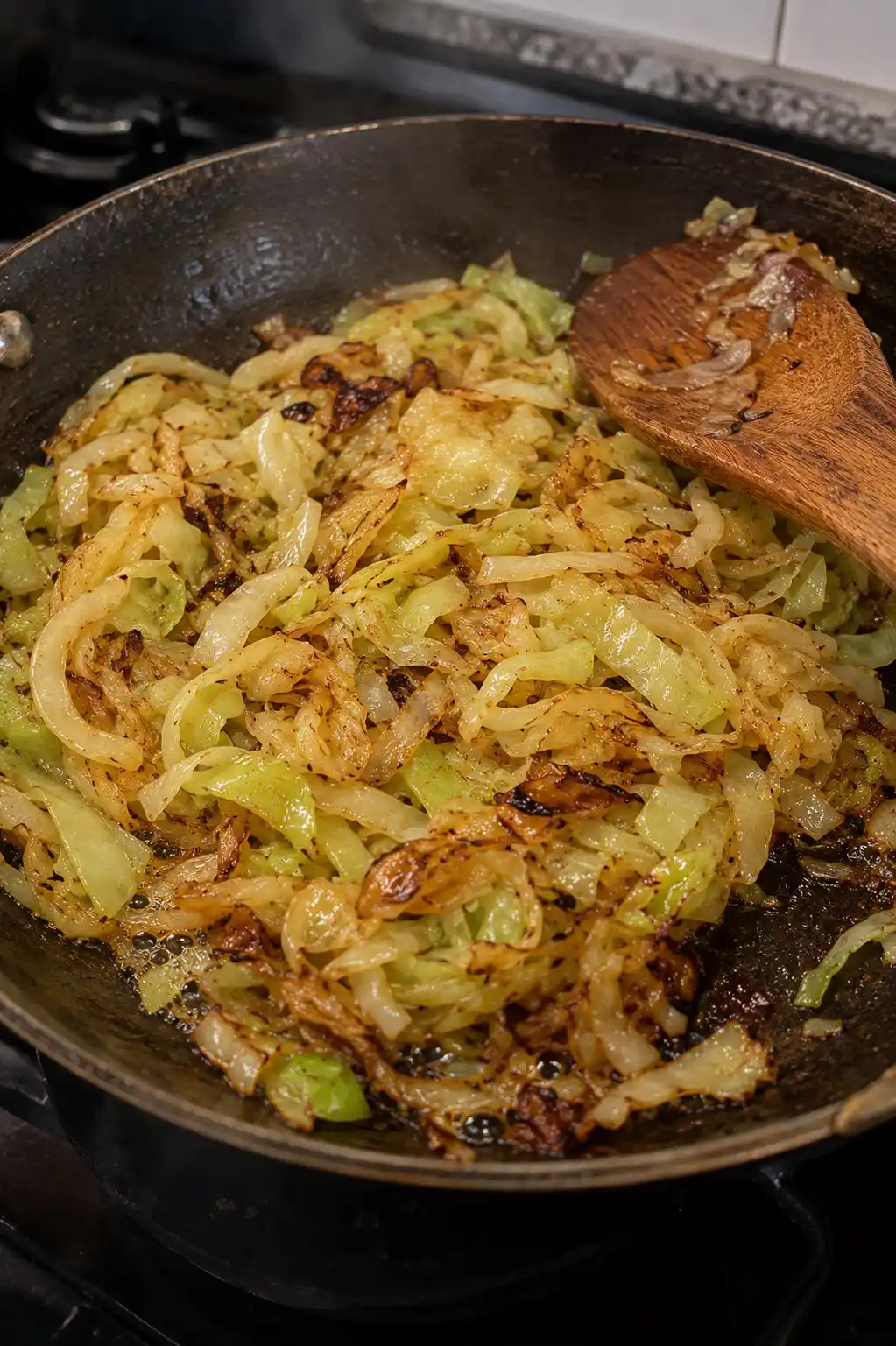 Thinly sliced cabbage caramelizing golden brown in a skillet with butter