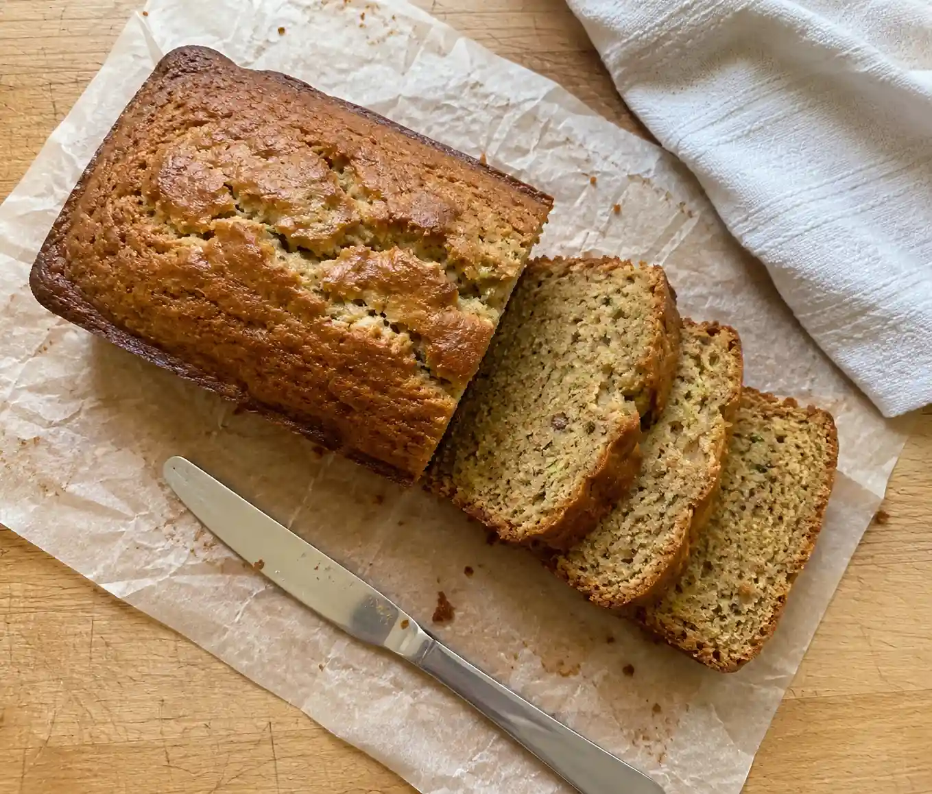 Sliced homemade zucchini bread Recipe loaf on parchment paper with a moist tender crumb