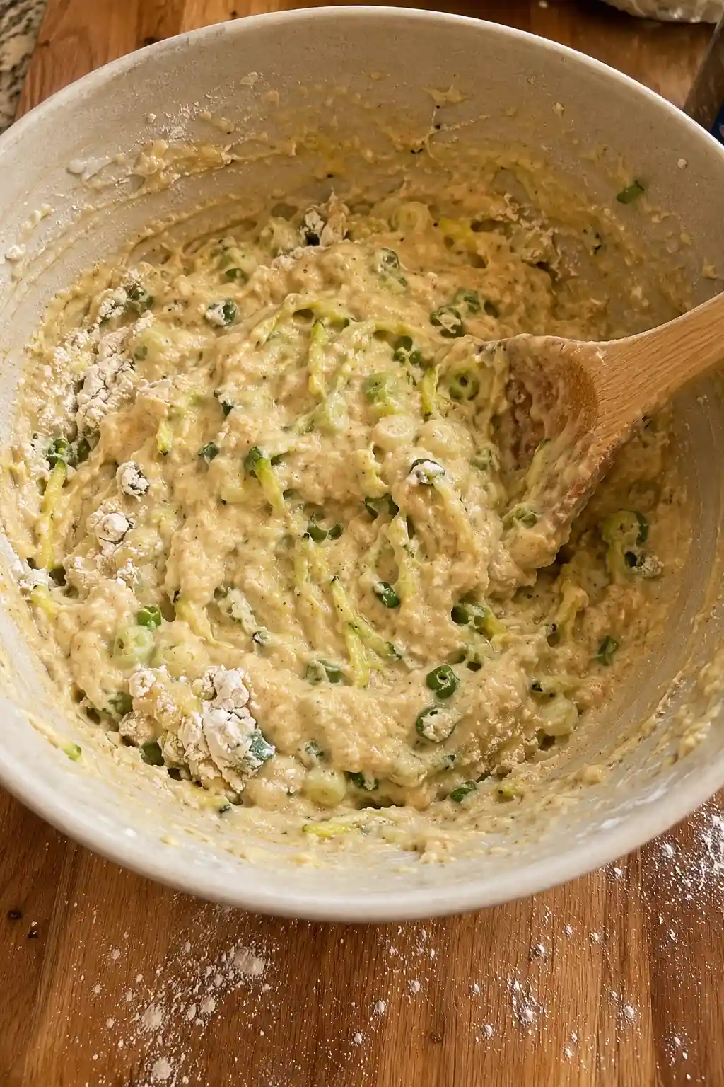 Thick zucchini fritter batter being stirred together with green onion and eggs