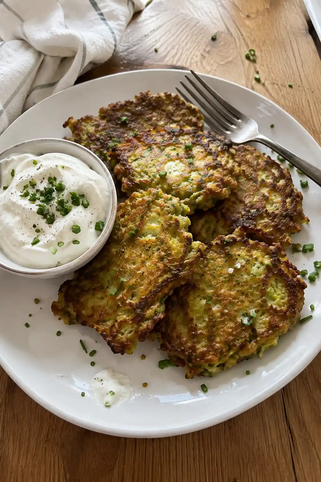 Plate of crispy zucchini fritters served with sour cream and fresh chives